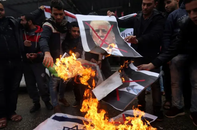 Palestinians burn posters depicting U.S. President Donald Trump and Israeli Prime Minister Benjamin Netanyahu during a protest against the U.S. intention to move its embassy to Jerusalem