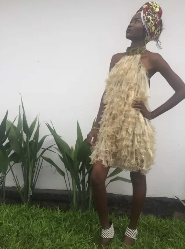 A woman poses in a dress made of condoms