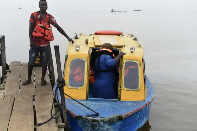 A woman boards a boat tied to an old jetty