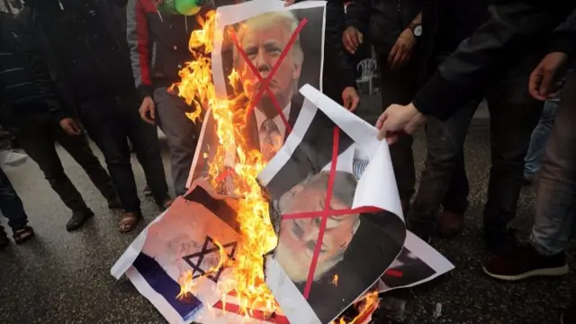 Palestinians burn Israeli and US flags and posters of US President Donald Trump and Israeli Prime Minister Benjamin Netanyahu during protest against the US intention to move its embassy to Jerusalem and to recognize the city of Jerusalem as the capital of Israel, in Rafah, the southern Gaza Strip, 6 December 2017