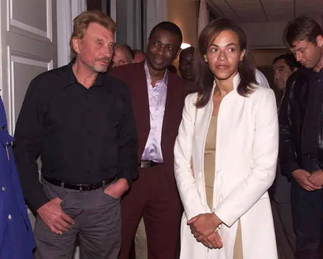 French singer Johnny Hallyday (L) is seen with Senegalese singer Youssou Ndour (C) and Sindyeli Wade (R), daughter of Senegal's President Abdoulaye Wade, 14 January 2002 in Dakar, Senegal