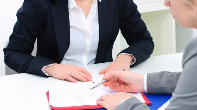 Two people look at a note on a clipboard