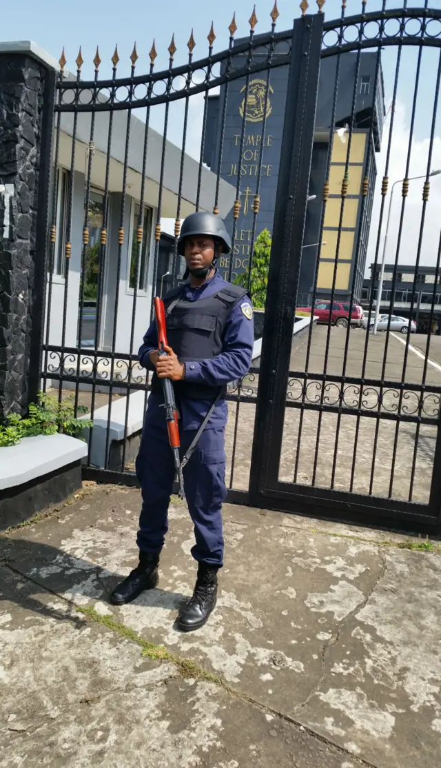 An armed police officer stands outside the court in Liberia