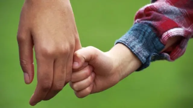 Child holding adult's hand