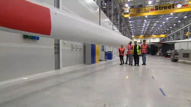 Young people next to a wind turbine blade in Siemens factory