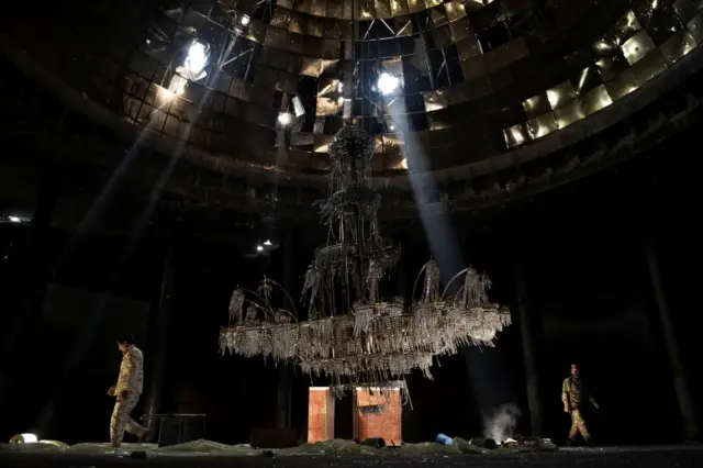 Fighters of the Libyan forces affiliated to the Tripoli government walk around the gigantic chandelier of the conference room in Ouagadougou Congress Complex