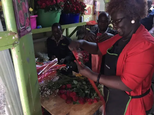 Flower seller arranges bouquet of red roses for Valentines day