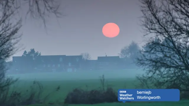 Sun setting over misty village scene