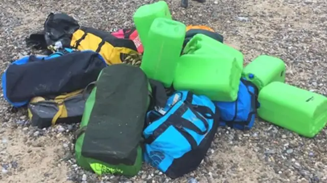 Holdalls on the beach, with buoyancy aids