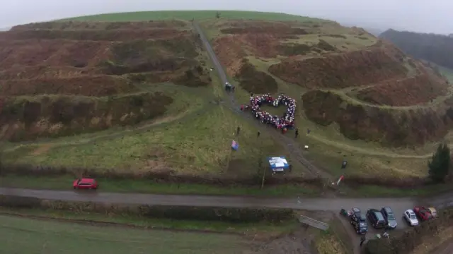 People forming heart on hill fort