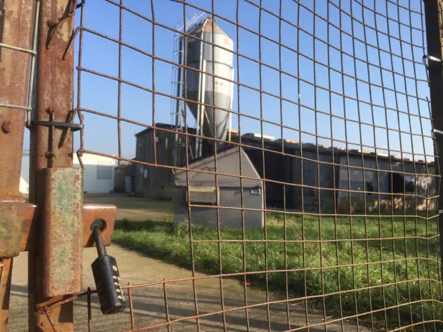 Outbuildings seen through padlocked gate