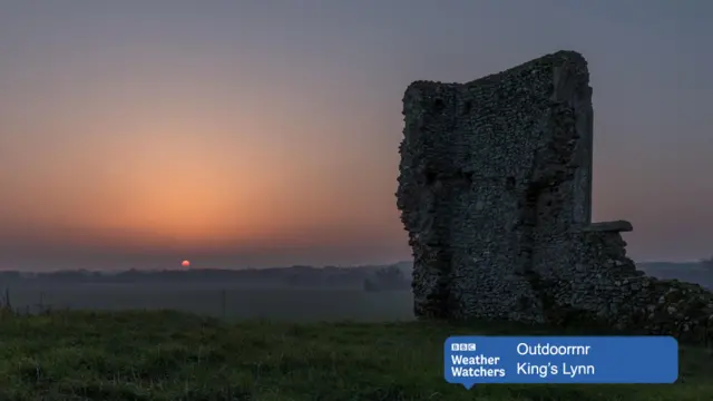 Sunrise over meadows, with architectural ruin in foreground