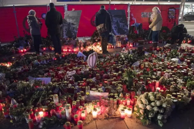 Passersby pause at a memorial for the Christmas market terror attack victims at Breitscheidplatz on January 19, 2017 in Berlin, Germany.