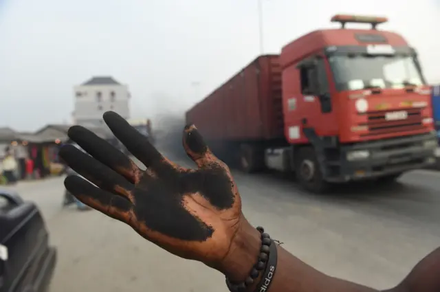 A Port Harcourt resident show a hand stained with soot from touching a car