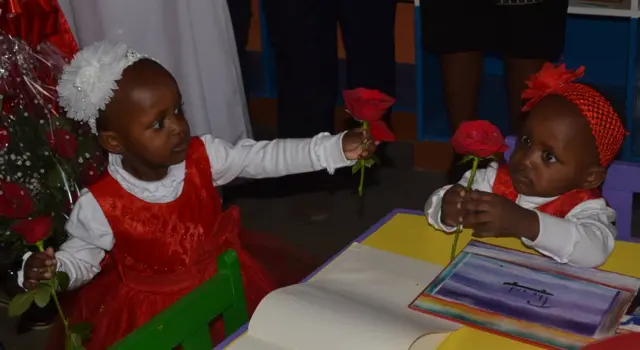 Twin sisters Blessing and Favor offer each other red roses inside the hospital