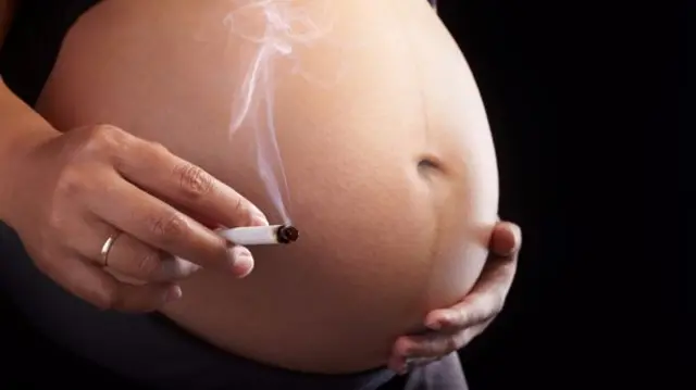 Cigarette next to pregnant belly