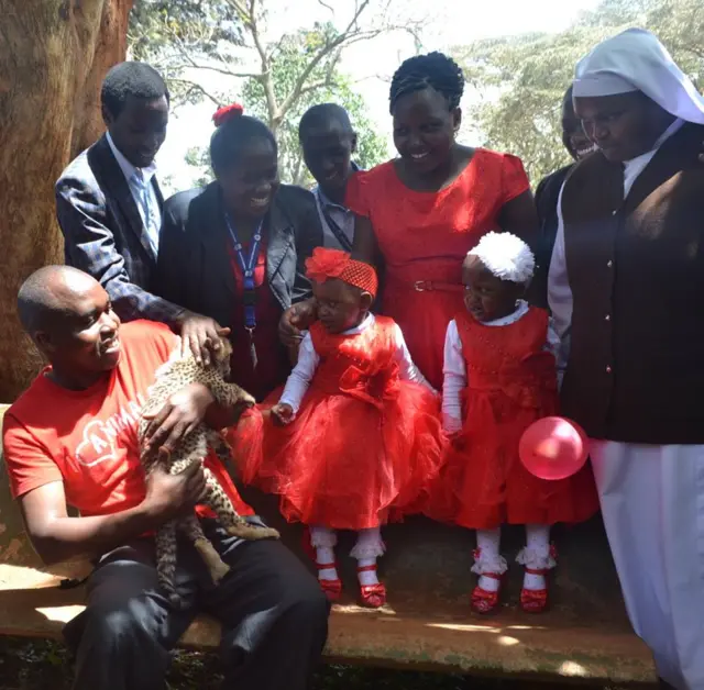 The two sisters look on with trepidation while a keeper presents them with a baby cheetah for them to pet