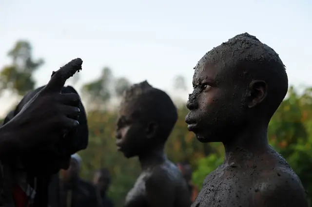 Boy has mud smeared on his face as part of a ritual circumcision ceremony