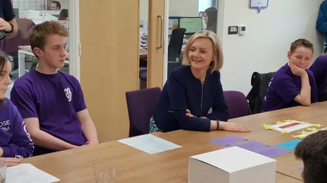 A closer image of Liz Truss seated, with youngsters