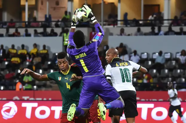 Cameroon"s goalkeeper Fabrice Ondoa (C) saves a shot on goal by Ghana"s forward Andre Ayew (R) next to Cameroon"s defender Adolphe Teikeu