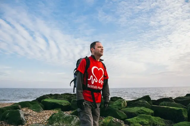 Kieran Sandwell, standing on a shingle beach