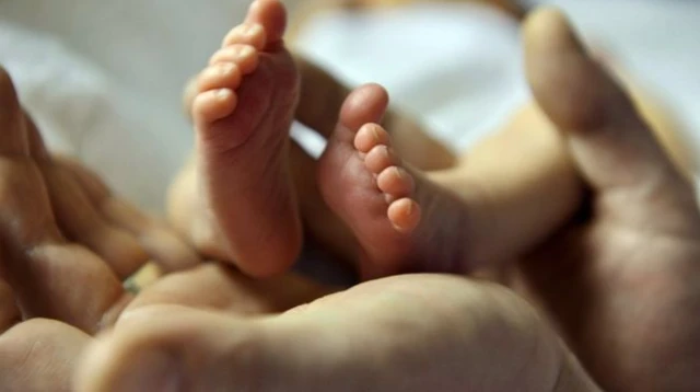 Hands clasped holding a newborn baby's feet