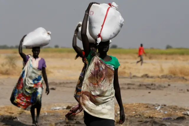 Women carrying sacks of food in the village of Nimini, South Sudan