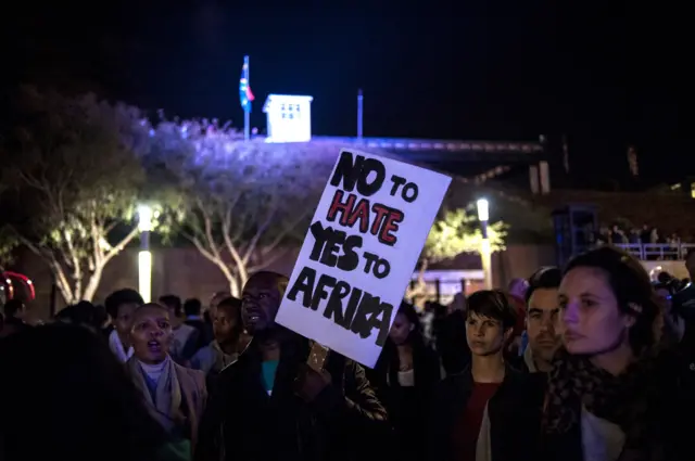 A man holds a placard as he and others attend a silent vigil against xenophobia, held at Constitution Hill in Johannesburg on April 21, 2015.