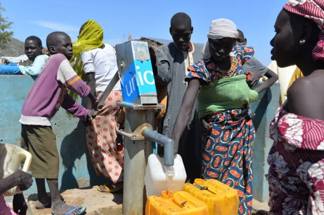 People collect water from a pump on November 13, 2014 in a UNHCR camp for Nigerian refugees in Minawao, in the extreme north-west of Cameroon