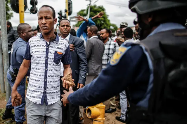 Somali migrant holds rocks in Marabastad area