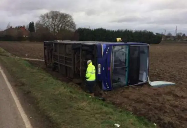 Overturned double-decker bus, lying in a field