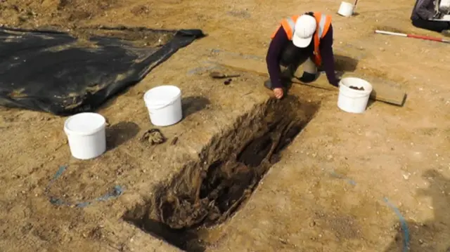 Archaeologist at work on one coffin, containing skeleton