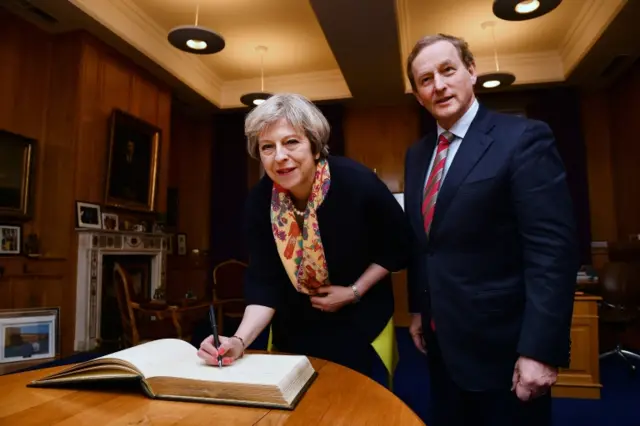 
          British Prime Minister Theresa May signs the visitors book watched by Irish Taoiseach Enda Kenny at Government Buildings
        