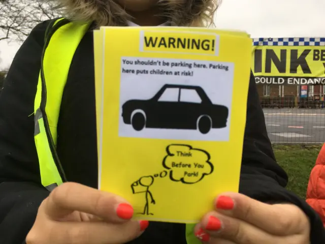 A yellow sign asking motorists not to park where dangerous