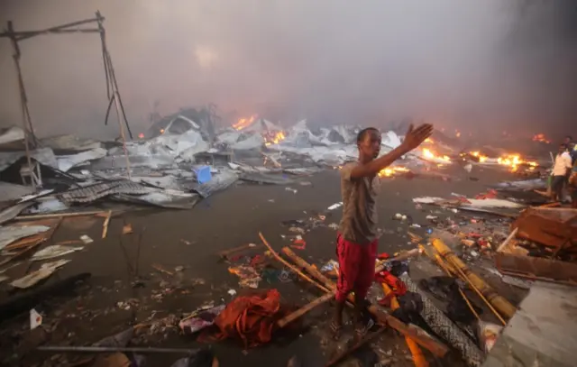 
          A Somali trader talks to residents gathered near the burning stalls at the main Bakara market
        