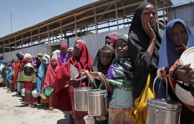 
          Somali girls who fled the drought in southern Somalia stand in a queue to receive food handouts at a feeding center in a camp in Mogadishu, Somalia
        