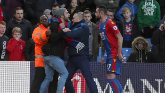 A fan gets on the pitch to argue with Delaney