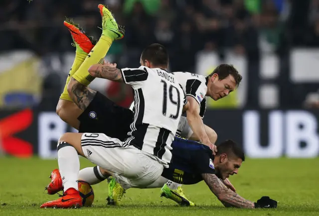 Inter Milan's Mauro Icardi falls as he vies for the ball with Juventus defenders Leonardo Bonucci and Stephan Lichtsteiner