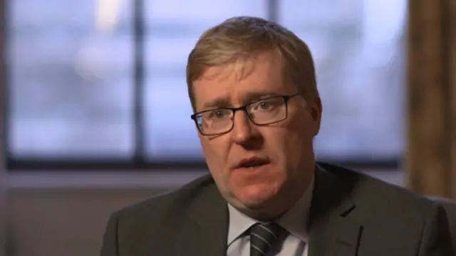 Richard Murray, in dark grey suit, light grey shirt and striped grey tie, wearing glasses