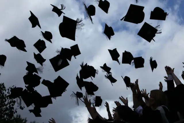 Graduates throw their mortar boards into the air