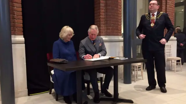 Charles and Camilla sign the visitors book at the Ferens