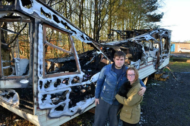 Rhys and Megan Bowen with their cat outside their burnt out caravan