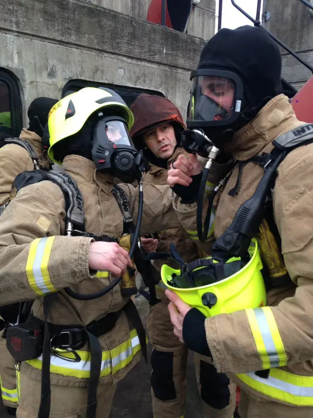 Current trainee firefighters tightening straps on masks