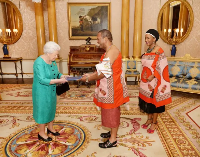 
          Britain's Queen Elizabeth II greets the High Commissioner of Swaziland, Christian Muzie Nkambule, and his wife, during a private audience with at Buckingham Palace in central London
        