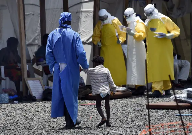 
          A nurse walks with a little girl suffering from Ebola, at the international medical NGO Medecins Sans Frontieres (MSF) in Monrovia on September 27, 2014
        