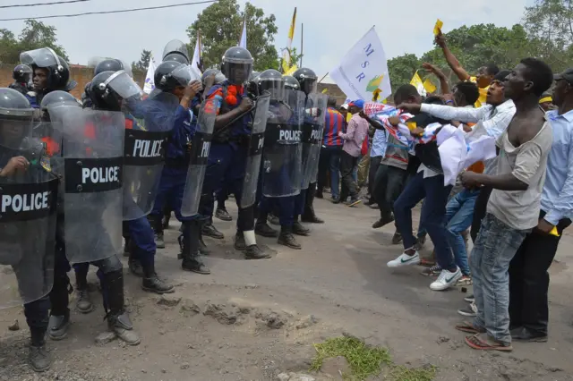 
          People holding placards and facing Congolese anti-riot policemen in DR Congo
        