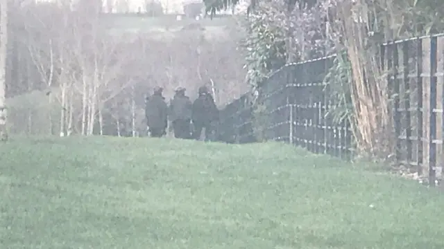 Police officers at a fence backing onto street