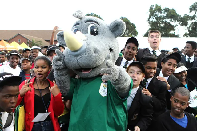 Crowd of children surrounds mascot in rhino outfit