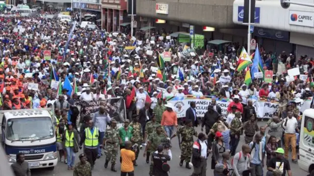 Crowd of people march through a street