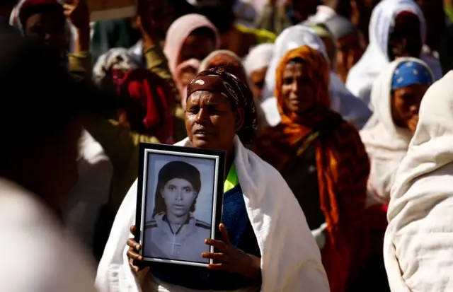 
          A woman carries a photograph as she mourns her family members suspected to be missing following a landslide
        